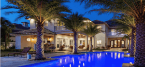 Night picture of lighted house, pool,and landscaping around a pool