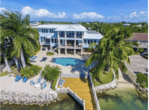 Upper Keys luxury homes for sale slide show of home with pool, wooden pier, and sandy beach.