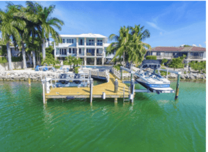 Upper Keys luxury homes for sale slide show. Photo of house on the waterfront with a wood pier, boat lift, landscaped backyard.